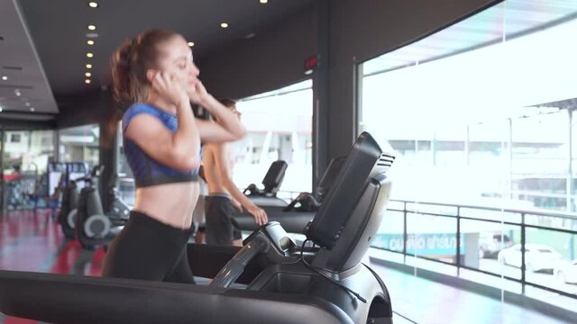 Happy woman running on treadmill in gym