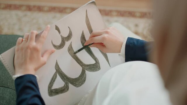 Pregnant Muslim woman writes to Allah.Close-up hands. Shoot from the shoulder.