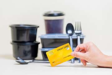 Online shopping, E-commerce, Internet banking, Spending money Concept - Woman holding yellow credit card and Different containers with delicious food on table. Selective focus and Copy space