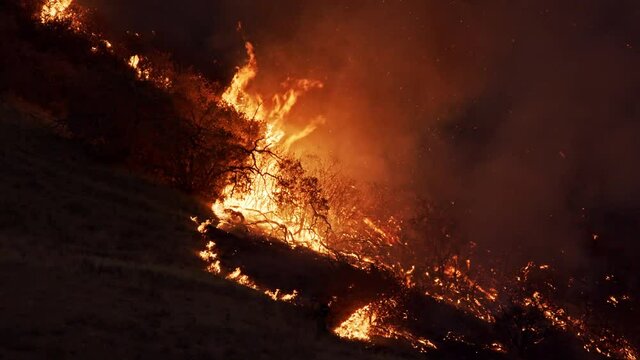 Sparks and ash fly in the air from flames of wildfire in Utah burning on the mountainside in Springville.