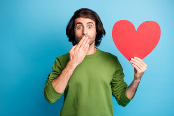 Photo of crazy amazed guy presenting heart form hand close mouth wear green pullover isolated blue color background