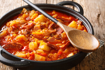 Spicy slowly stewed Locro made from vegetables, sausages and meat close-up in a pot on the table. horizontal