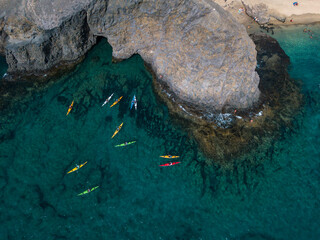 Aerial view of canoes sailing near the rugged coastlines and beaches of Lanzarote, Spain, Canaries. Explore the island. Bathers on the beach and in the Atlantic Ocean. Papagayo