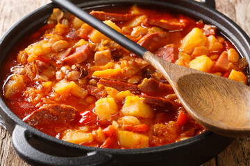 South American Locro stew of pumpkin, beans, corn and meat close-up in a pot on a table. horizontal