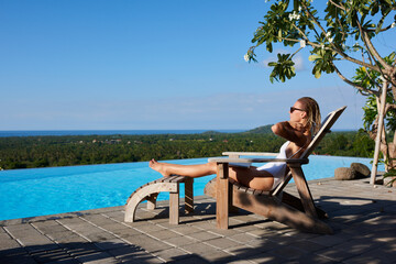 Female tourist lounging on deckchair near swimming pool