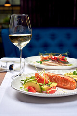 A glass of wine and fish dishes in a restaurant.