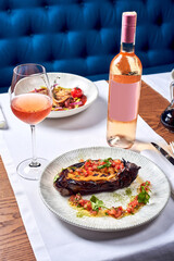 A bottle of wine and a dish of zucchini in a restaurant.
