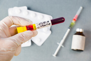 Covid - 19 negative blood test sample in doctors hand whit white glove, vaccine ampule and needle