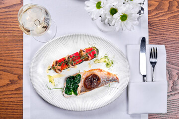 A platter of pike perch and a glass of wine on a table. View from above.