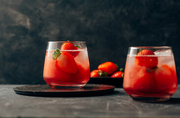  two strawberry cocktail with ice on dark background