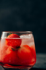 Delicious strawberry cocktail with ice on dark background