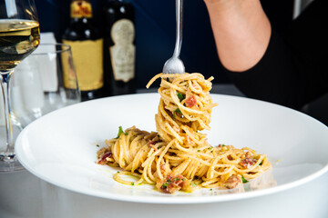 Eating italian spaghetti carbonara with white wine