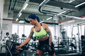 Fototapeta na wymiar tattooed young woman exercising in the gym
