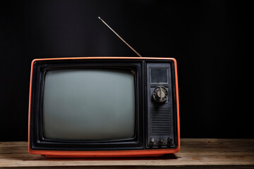 Retro old TV on wooden table in room with black background