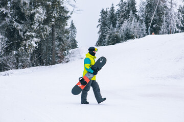 Fototapeta na wymiar man with snowboard walking by snowed hill