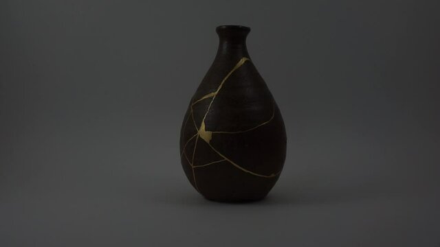 Kintsugi bizen sake bottle. Bright gold cracks lighted up. Fragile cracks trauma representation. Psycology.