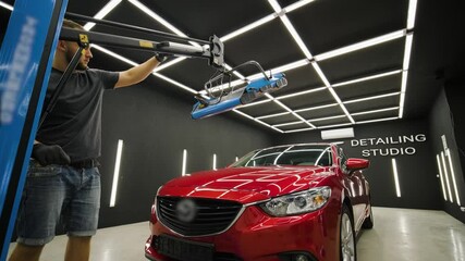Red lamps for drying the ceramic coating are behind car