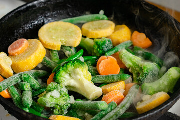 Frozen vegetables in a pan. Mix of different vegetables - carrots, green beans, cauliflower.