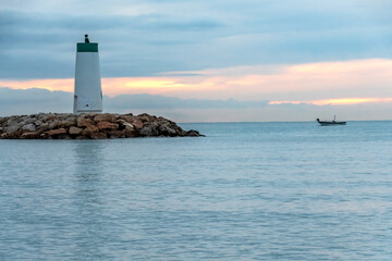 Obraz premium Lever de soleil sur la mer près du phare du port de Villeneuve Loubet sur la Côte d'Azur