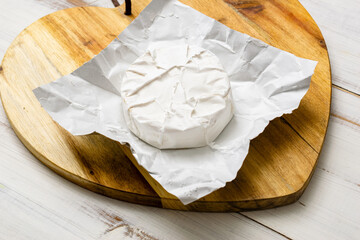 Round piece of camembert cheese on a wooden background.