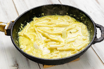 Fried squid in a pan in a creamy sauce.