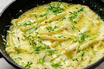 Fried squid in a pan in a creamy sauce with sprouted mustard seeds.