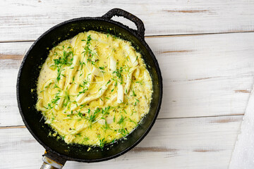 Fried squid in a pan in a creamy sauce with sprouted mustard seeds.