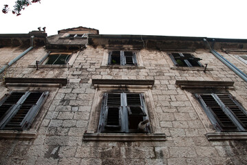 Fototapeta na wymiar Windows in stone house with close sun shutters