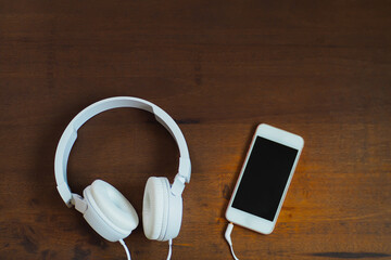 White headphones and mobile phone on the wooden floor
