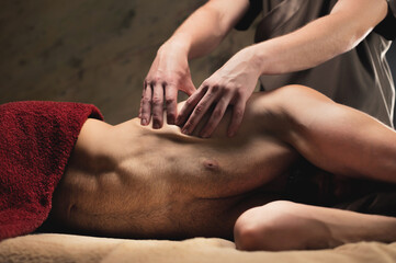 Physiotherapist giving Sports breast massage to bearded athlete in dark room of spa salon