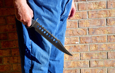 Huge Bowie knife being held by a mature caucasian male.  Violent crime or terrorism concept