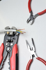 wire stripper, shielded three-core wire and wire cutters on a white background. close-up