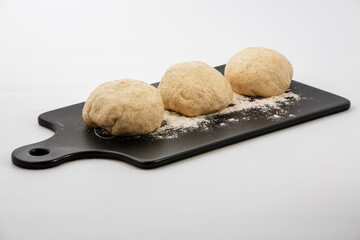 A round pieces of homemade white dough for pizza, bread or baking goods on a cutting board. Small pieces of dough ready to be baked. Healthy natural family food. Side view, daylight, home