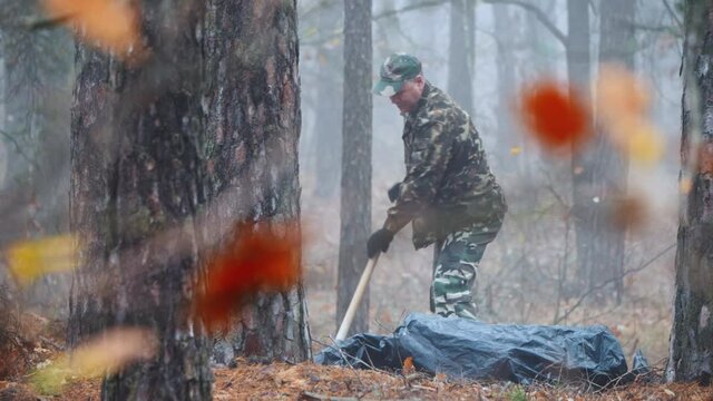 Behind tree branches, a criminal burys the victim's corpse