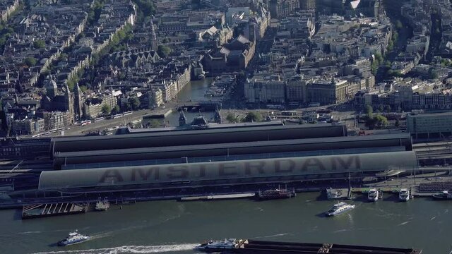 Aerial view of the famous Amsterdam Centraal Station, the largest railway station in Netherlands. Many ferries and cargo ships in the IJ. 