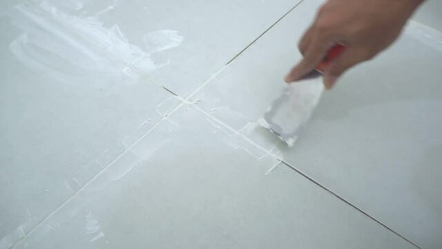 Grouting tile seams with a stainless steel trowel.Grouting ceramic tiles.	
