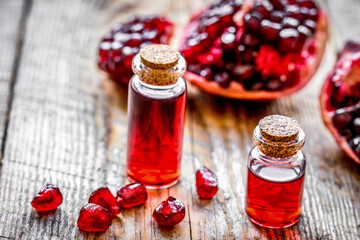 sliced pomegranate and extract in glass on wooden background