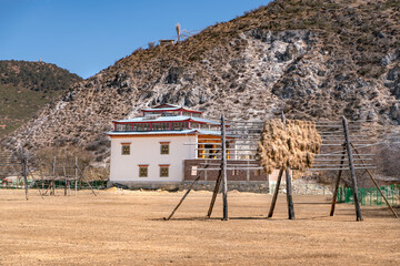 The view of traditional tibetan house and way of hay dries on wooden logs in Shangri-La on Tibet
