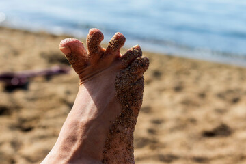 Part of the woman's foot in the sand, close-up.