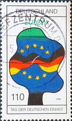 GERMANY - CIRCA 1998 : a postage stamp from Germany, showing a graphic of a tree with the German and European flags and the silhouette of Germany on the Day of German Unity