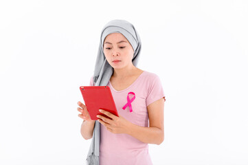 Asian women wear pink ribbons to their tops. Is using a red tablet on a white background. Breast cancer concept, cancer prevention concept.