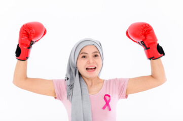 Muslim religious women in hijab put a pink ribbon on their tops. And wearing boxing gloves on a colored background. Breast cancer concept, cancer prevention concept.