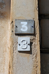 Close Up of Small Metal Plaques with Number 3 on Old Textured Wall