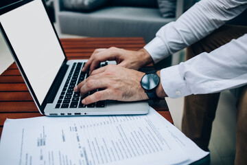 Cropped image of male's hands keyboarding on laptop computer with blank copy space screen, man freelancer typing text of publication share on web site online working distantly.