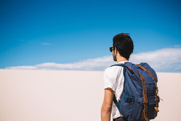 Male traveller standing under heating sun rays during journey to White sands national park, guy wanderlust standing outdoors with breathtaking view of desert and sky horizon over dry uninhabited lands