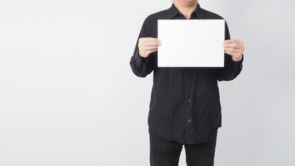 Male asian wear black shirt and hand is holding blank paper on white background.Empty space for text.