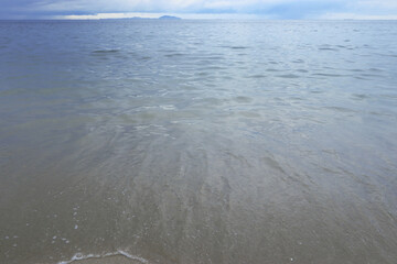 The sea has sparse waves on the coast.