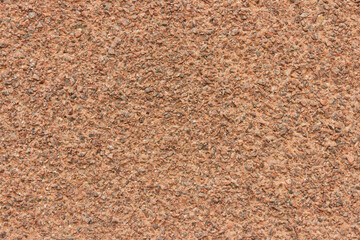The surface of a rough uneven wall, plastered with fine marble chips.