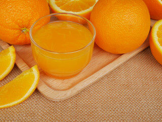 A cup of orange juice and many oranges on cutting board