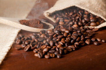 powdered coffee (ground), on wooden spoon, with smoke and coffee beans, with raffia cloth bag, brown background